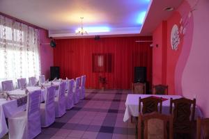 ein Festsaal mit weißen Tischen und Stühlen und roten Wänden in der Unterkunft Hotel Ludza in Ludza