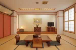 sala de estar con mesa, sillas y TV en Nozawa Onsen Utopia, en Nozawa Onsen