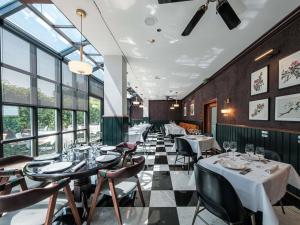 een restaurant met tafels, stoelen en ramen bij Mercure Hotel Frankfurt Airport Langen in Langen