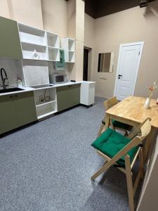 a kitchen with a wooden table and green cabinets at Sky Tau Hostel in Almaty
