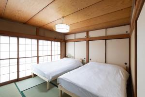 two beds in a room with wooden ceilings and windows at Kotori Ayase in Tokyo +60 photos