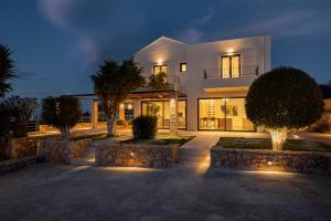 a large white house with trees and lights at Plaka Oasis - Private Pool - Walk to Beach & Shops in Plaka