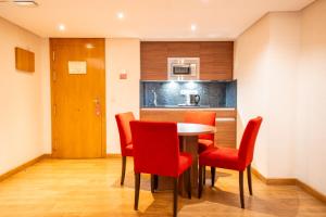 ein Esszimmer mit einem Tisch und roten Stühlen in der Unterkunft Aparto-Hotel Rosales in Madrid