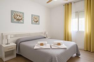 a white bedroom with a bed with two white towels at Alojamiento Baeza- El Limonero A in Baeza