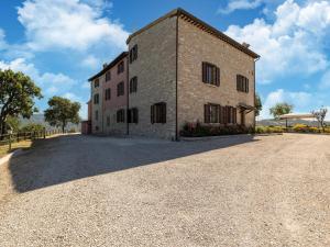 een groot bakstenen gebouw op een grindweg bij Apartment in a farmhouse with 2 swimming pools in Cagli