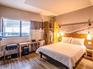 a hotel room with a bed and a desk and a window at ibis Palmas Avenida JK in Palmas