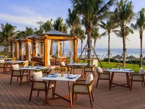 un restaurant sur la plage avec tables et chaises dans l'établissement Mövenpick Resort Cam Ranh, à Cam Ranh