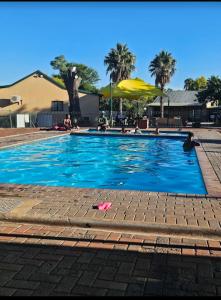 a swimming pool with blue water and palm trees at Unit 35 Pendleberry grove holidays in Bela-Bela