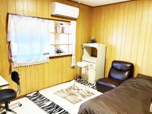 una camera da letto con un letto, una sedia e una finestra di The Village House 1 a Hadano Altre 2 foto