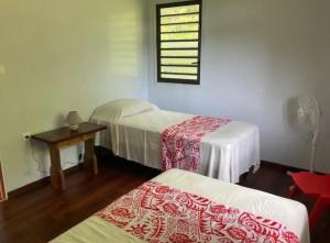 una stanza con due letti, un tavolo e una finestra di Te Fare Ninamu a Taputapuapea