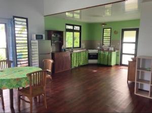 una grande cucina con pareti verdi, tavolo e sedie di Te Fare Ninamu a Taputapuapea Altre 3 foto