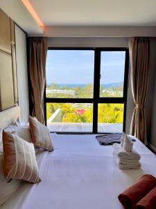 a bedroom with a large bed with a large window at Surin Beach View Phuket in Ban Lum Fuang