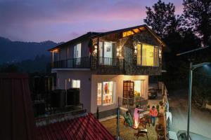 a family standing in front of a house at night at SaffronStays The Kumaoni Abode in Bhīm Tāl