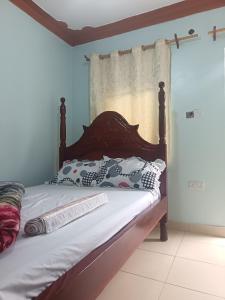 een bed met een houten hoofdeinde in een kamer bij Delight motel in Ishaka