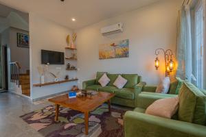 a living room with green couches and a coffee table at SaffronStays The Kumaoni Abode in Bhīm Tāl