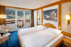 a bedroom with a large bed and a large window at Derby Swiss Quality Hotel in Grindelwald