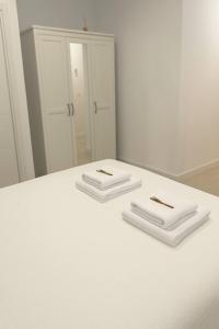 Twee witte handdoeken liggen op een witte tafel voor een spiegel. bij Alojamiento Baeza California 4A in Baeza