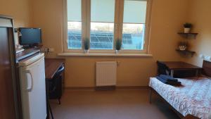 a bedroom with a bed and a desk and two windows at Dom Studencki Zbyszko in Poznań
