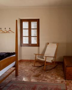 a bedroom with a bed and a chair and a window at The Winemaker's House - La Collina La Casa in Casa Berta