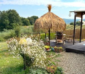 un ponte con un ombrellone di paglia e alcuni fiori di 2 CUORI E 1 YURTA Glamping in Tuscany - Adults Only ad Asciano