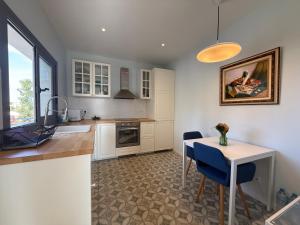a kitchen with white cabinets and a table with blue chairs at The White House in Calafell
