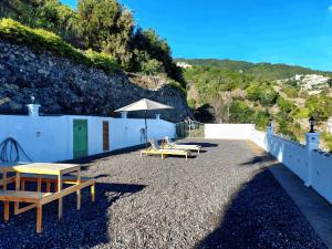 a patio with two picnic tables and an umbrella at Peluquina in Barlovento