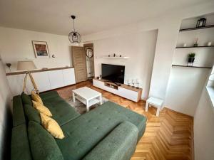 un soggiorno con un divano verde e una televisione di Tilia a Zaječar