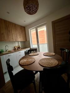 a kitchen with a wooden table with chairs and a dining room at Tilia in Zaječar +6 photos