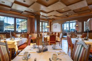 a dining room with tables and chairs and windows at Hotel Austria Wildschönau & Wildschönau Premium Card in Niederau