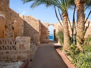 eine Gasse mit Palmen und einem Steingebäude in der Unterkunft Movenpick Resort El Quseir in Al-Qusair