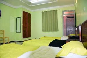 ein Zimmer mit drei Betten und einem Fenster in der Unterkunft Hotel el djawhara in Melika