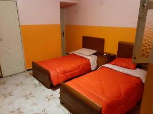 2 Betten in einem Zimmer mit orangefarbenen und gelben Wänden in der Unterkunft Hotel el djawhara in Melika