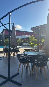 een terras met tafels, stoelen en een parasol bij Pousada Vista da Pedra in Itamaraju