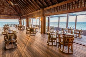 a restaurant with tables and chairs and the ocean at Hurawalhi Island Resort in Kuredu