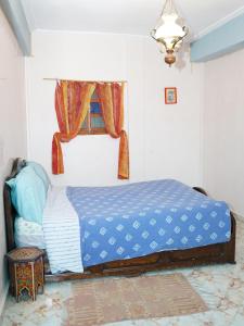 ein Schlafzimmer mit einem Bett mit blauer Bettdecke und einem Fenster in der Unterkunft Banana Aourir in Aourir