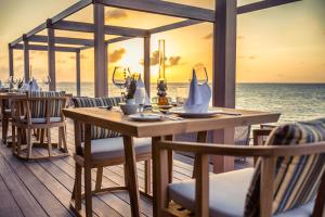 a restaurant on the beach with a table and chairs at Hurawalhi Island Resort in Kuredu