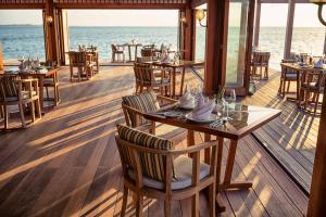 a restaurant with tables and chairs and the ocean at Hurawalhi Island Resort in Kuredu