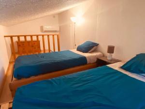 a bedroom with two beds with blue sheets on them at Maison en corse in Santa-Maria-Poggio
