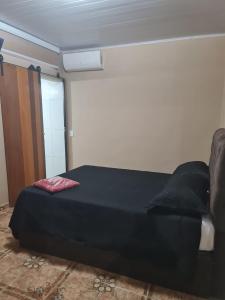 a bedroom with a bed with black sheets and pillows at Cananéia Apoio Tours in Cananéia