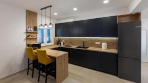 a kitchen with black cabinets and yellow bar stools at Villa Olea by Villas Guide in Blace