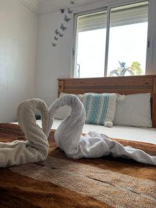 two towel swans sitting on the floor next to a bed at Black Pearl surf yoga and skate house in Tamraght Ouzdar