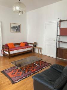 een woonkamer met een bank en een glazen tafel bij La Luciole in Périgueux