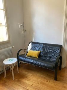 een zwarte leren bank in een kamer met een tafel bij La Luciole in Périgueux