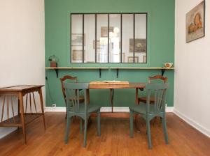 a table and chairs in a room with a green wall at La luciole in Périgueux