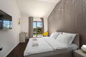 une chambre avec un grand lit blanc avec une fenêtre dans l'établissement Mediterrane Steinvilla mit Privatpool, toller Aussicht, starkem WiFi, BBQ, à Majkusi 27 autres photos