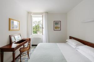 een slaapkamer met een bed, een bureau en een raam bij Residence L'Ulivo in Bellagio