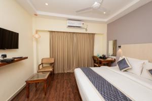 a hotel room with a bed and a desk and a room at The Grand Rajmahal in Bangalore