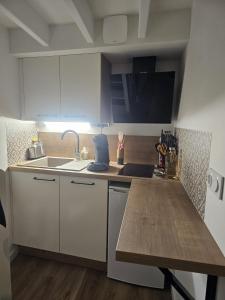 a kitchen with white cabinets and a sink and a table at Le Ptit nid in Château-Gontier