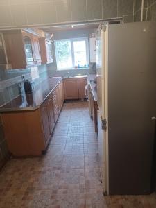 a kitchen with a refrigerator and a tile floor at Christian Guest House 1 in Luton