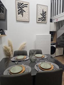 a dining room table with four chairs and a black table top at Le Ptit nid in Château-Gontier